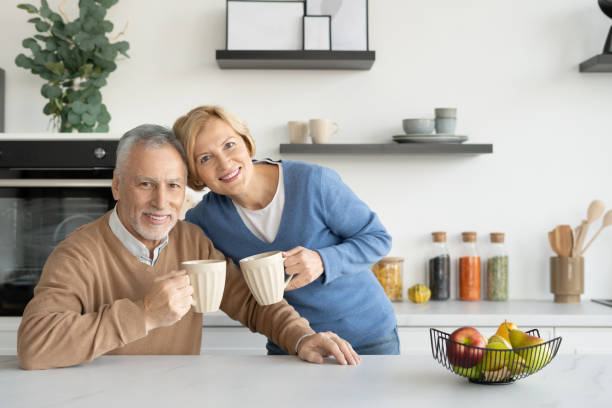 istock Smiling senior spouses holding cups and looking at camera 1387298346