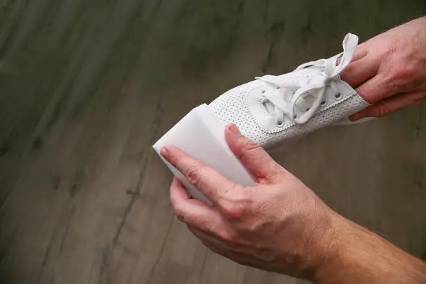 A man cleans white sneakers with  melamine sponge.