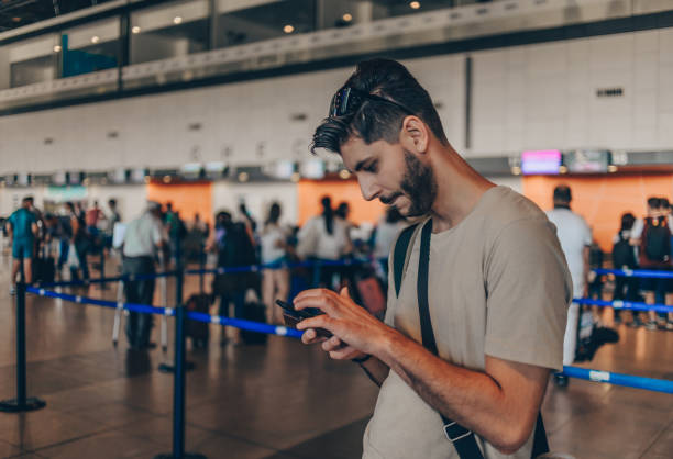 istock Joyful adult man is waiting for his departure while using mobile phone 1387300727