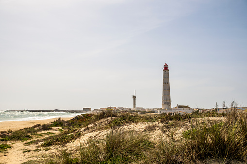 Beach, dunes and lighthouse at Farol Island, Faro District, Algarve, Portugal