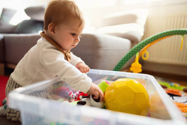 istock Caucasian baby boy, choosing the toy from the plastic container 1387307771
