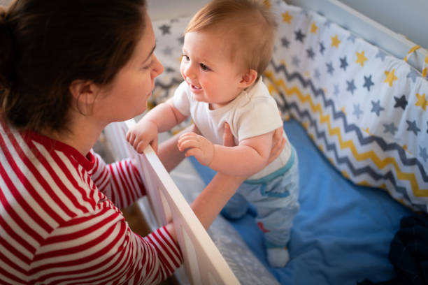 istock Mother holding her son, while he standing in the crib 1387308179