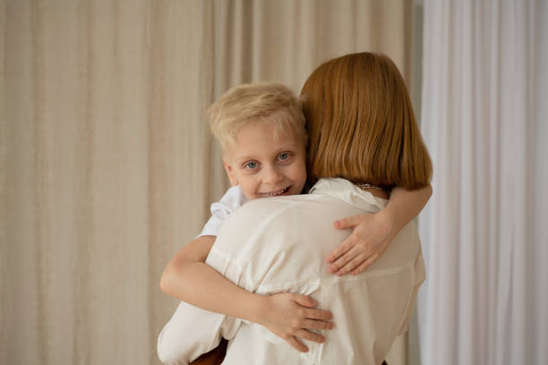Mom and son with blond hair spend a good time hugging. Portrait of a family in the interior. Mother's Day. The relationship of children and their parents.