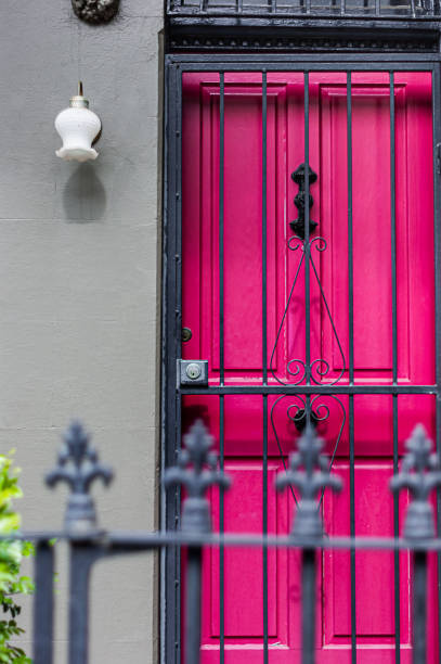 esterno della casa con una porta rosa brillante, cancello di sicurezza e recinzione decorata in primo piano - gate handle door traditional culture foto e immagini stock