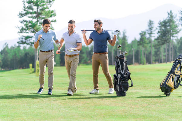男性ゴルファーの友人のグループは、ゴルフコースに立って話し、笑顔、美しい晴れた日にゴルフをプレイ - 大富豪 ストックフォトと画像
