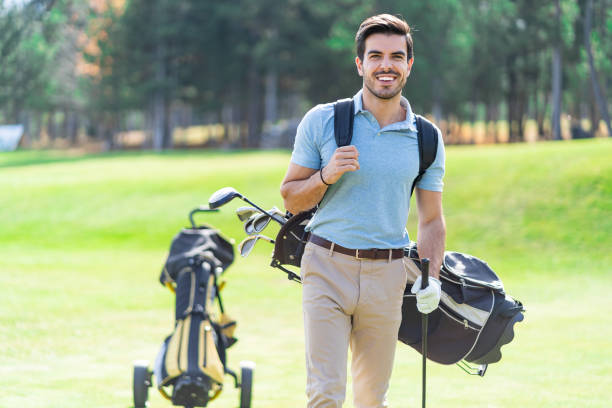 istock Smiling golf player standing on a golf course with a    backpack on his back and holding a golf club in his hand 1387310289