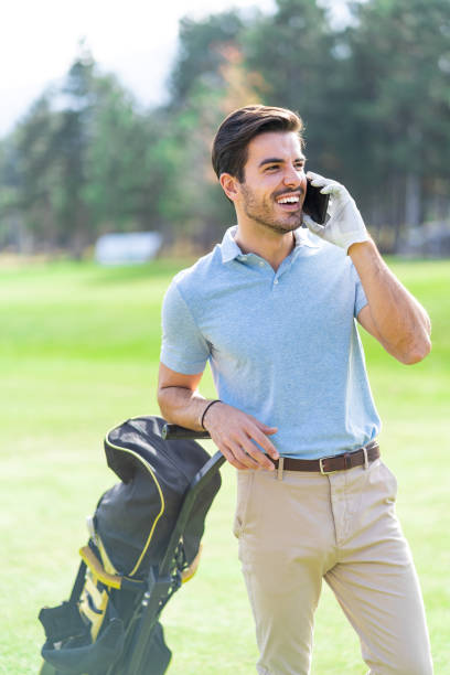 istock Smiling golfer talking on his mobile phone on the course while carrying his bag with golf clubs 1387310315