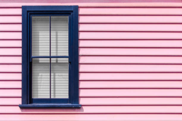 A dark blue window contrasts against a light pink weatherboard house exterior Exterior of a home with a dark blue window contrasting against a light pastel pink weatherboard exterior traditionally australian stock pictures, royalty-free photos & images