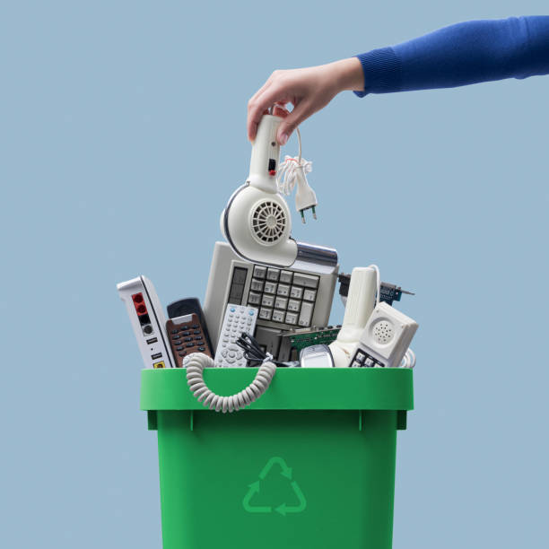 Woman putting an old appliance in the waste bin Woman putting an old broken appliance in the trash bin, e-waste and recycling concept e waste photos stock pictures, royalty-free photos & images