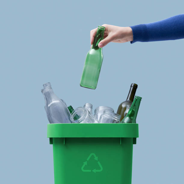 istock Woman putting a glass bottle in the trash bin 1387310566