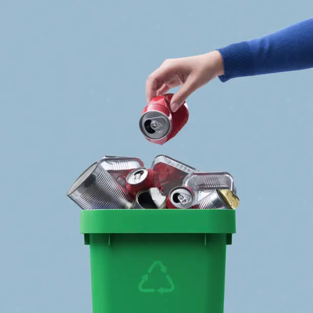 Woman throwing a metal can in the recycling bin, separate waste collection concept