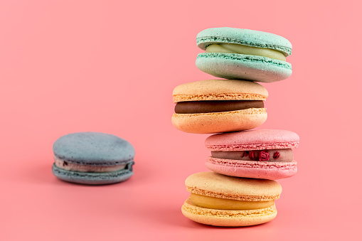 Macaroons stacked on a pink background. Delicious dessert of French cuisine, creatively decorated on a pink background