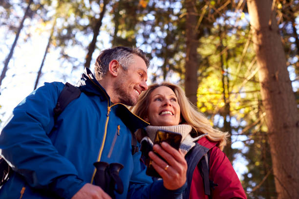 istock Mature Retired Couple Walk In Fall Or Winter Countryside Using Map Or Navigation App On Mobile Phone 1387313307