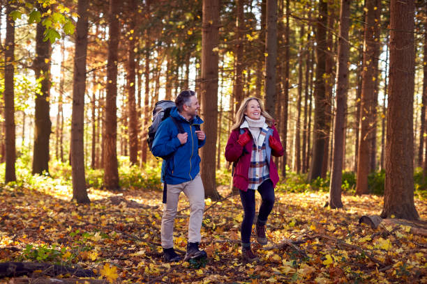 Mature Retired Couple With Backpacks Walking Through Fall Or Winter Countryside stock photo