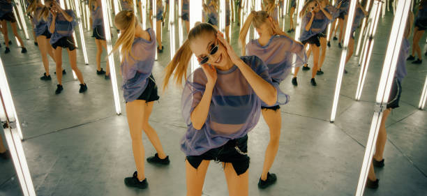 Woman in an infinity mirror room. Dancing and enjoying herself Woman in a mirror maze performing a dance. Multiple angle view never ending photos stock pictures, royalty-free photos & images