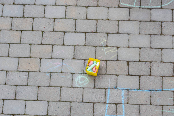 A five year old girl reaches for a pink stick of chalk.