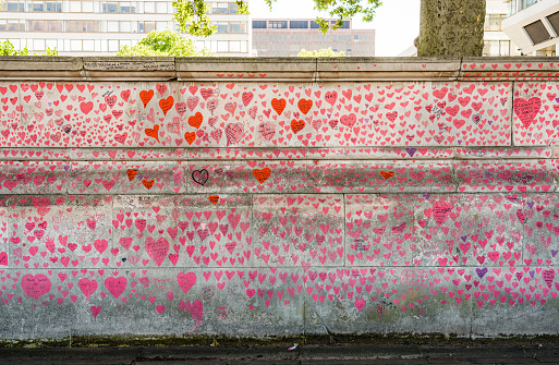London, UK - A small section of the National Covid Memorial Wall,  located on the South Bank of the Thames in central London, with each of the many thousands of red hearts and written personal dedication  representiing a victim of the Covid-19 pandemic in the UK.