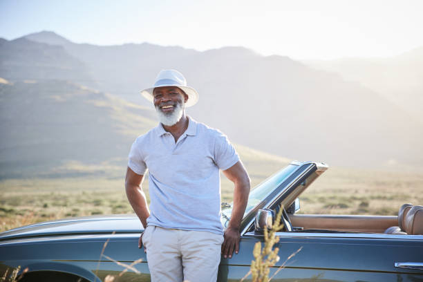 istock Laughing mature man leaning on his convertible during a break from a scenic drive 1387322373
