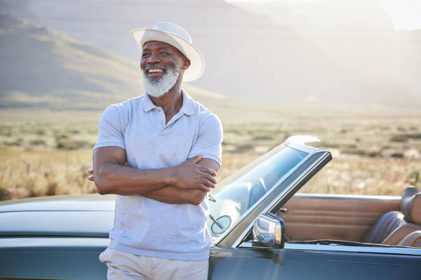 istock Laughing mature man standing by his convertible during a break from a scenic drive 1387322480