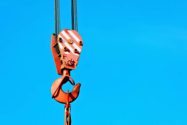 istock Crane hook with metal cable against blue sky. Unloading or loading of goods 1387323155