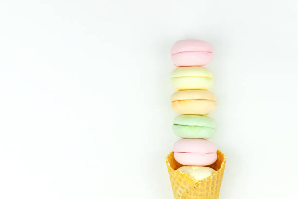 istock Layout with waffle cone cornet and colored marshmallows looks like macaroons on white background. 1387323596