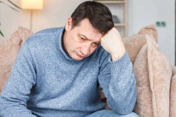 istock Unhappy middle-aged 50s man sit on couch 1387323860