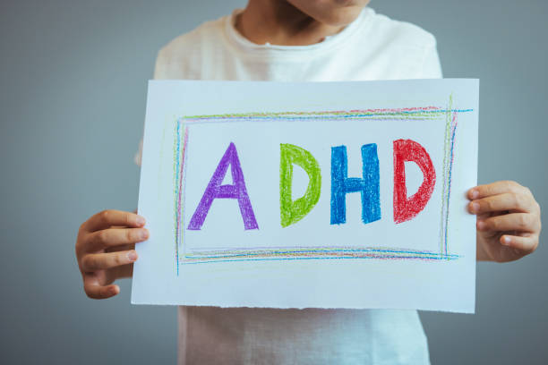 istock Young boy holds ADHD text written on sheet of paper. 1387324010