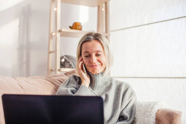 istock Happy middle aged woman using her laptop on the sofa at home 1387324731