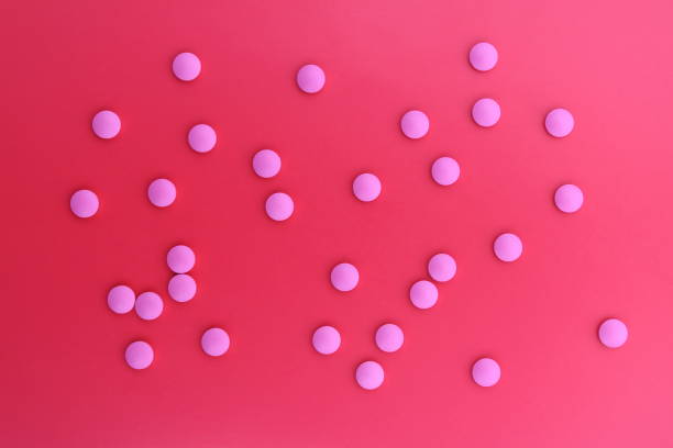 istock Background of pink pills on a red sheet. 1387325232