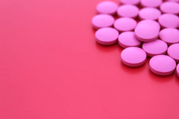 istock Pink pills lie on a red background with space for text. 1387325261