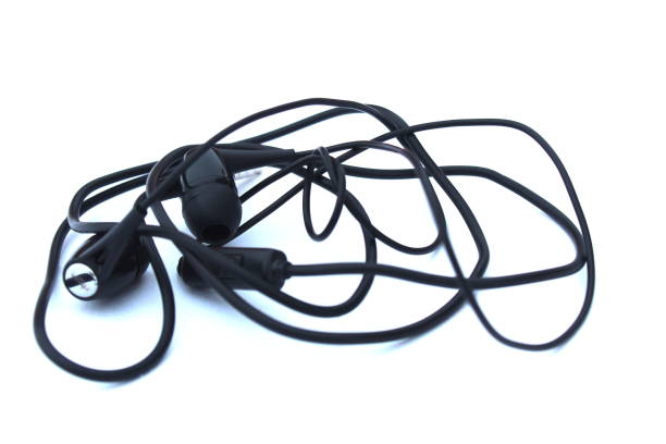 istock Black twisted headphones lie on a white background. 1387325263