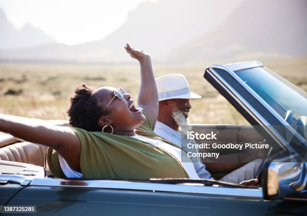 Woman laughing during a scenic road trip with her husband in a converitble
