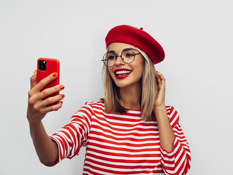 Sensual french woman wearing red beret and taking selfie