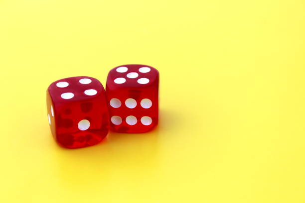 istock Red dice with white markings on a yellow background with space for text. 1387325553