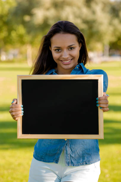 istock Beautiful woman holding a shalkboard 1387326246