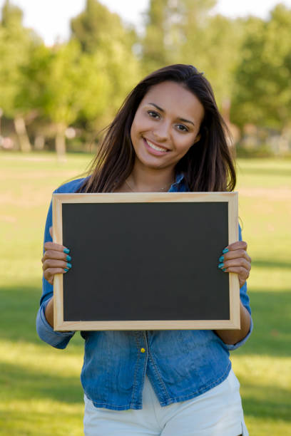 istock Beautiful woman holding a shalkboard 1387326247