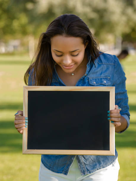 istock Beautiful woman holding a shalkboard 1387326250