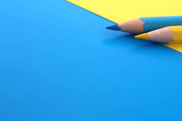 istock Yellow and blue pencils lie on the same color background with space for text. 1387326267