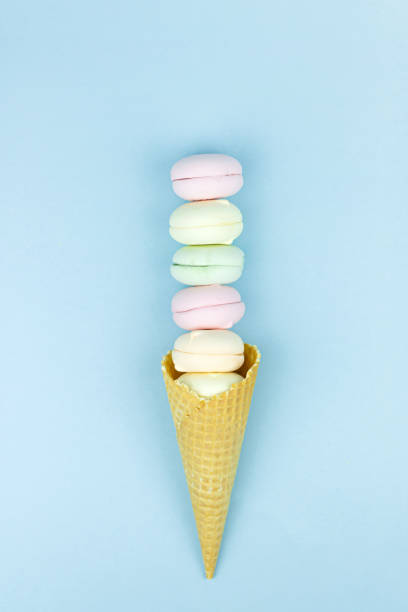 istock Waffle horn with colored marshmallow macaroons looks like ice cream on a blue pastel background. 1387326580