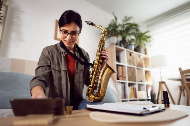 istock Female saxophonist, improving her skills while follow advanced tutorials on mobile phone 1387326700