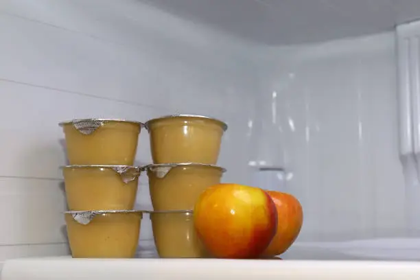 Individual  containers of applesauce inside of a fridge
