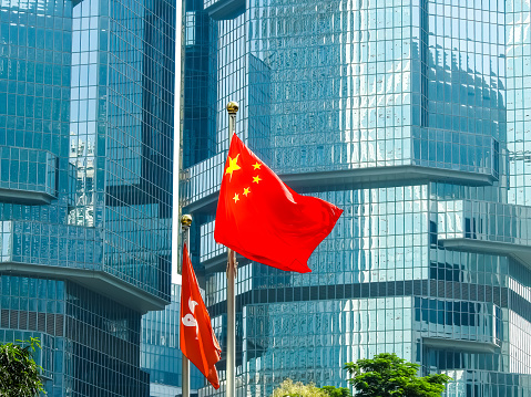 Hong Kong, China - September 14 2019: Hong Kong and China flags, and glass skyscrapers