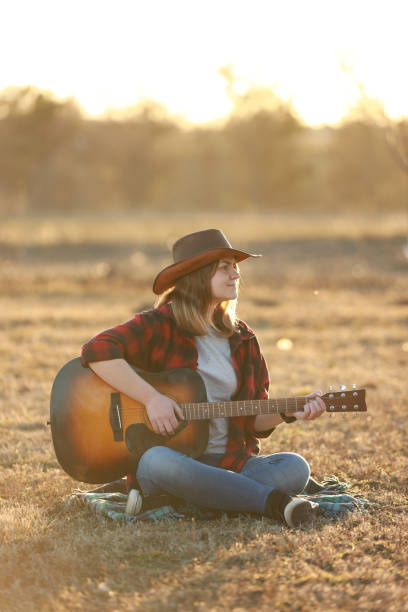 istock cowgirl with guitar at sunset 1387339814