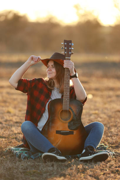 kowbojka z gitarą o zachodzie słońca - 20s acoustic guitar adult art zdjęcia i obrazy z banku zdjęć