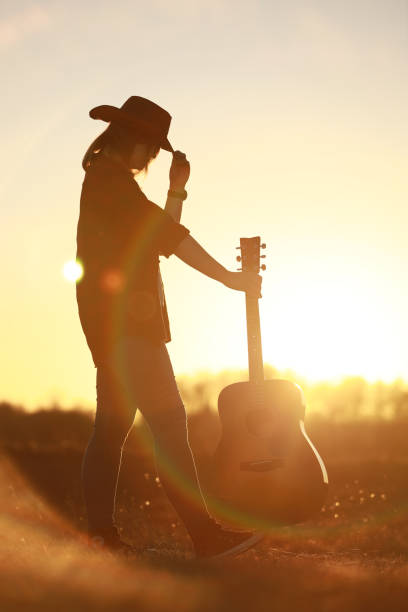 istock cowgirl with guitar at sunset 1387339932
