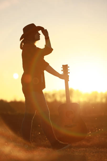 istock cowgirl with guitar at sunset 1387339934