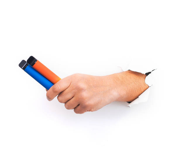 istock Two Disposable electronic cigarettes in hand closeup on a white background with shadows. The concept of modern smoking, vaping and nicotine. Copy space 1387343005