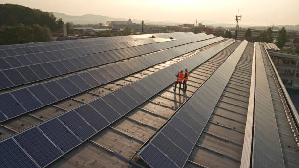 Engineers using laptop on rooftop Mature men engineer working on laptop while standing on the rooftop of solar power plant. two men same clothes stock pictures, royalty-free photos & images