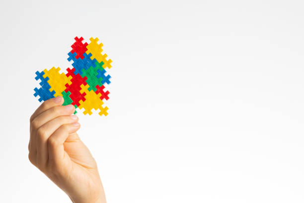 World autism awareness day concept. Child hands holding colorful puzzle heart on white background stock photo