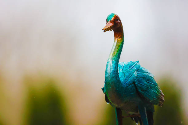 A completely blurred background of nature with a metal yard decoration, a bird, in the foreground.